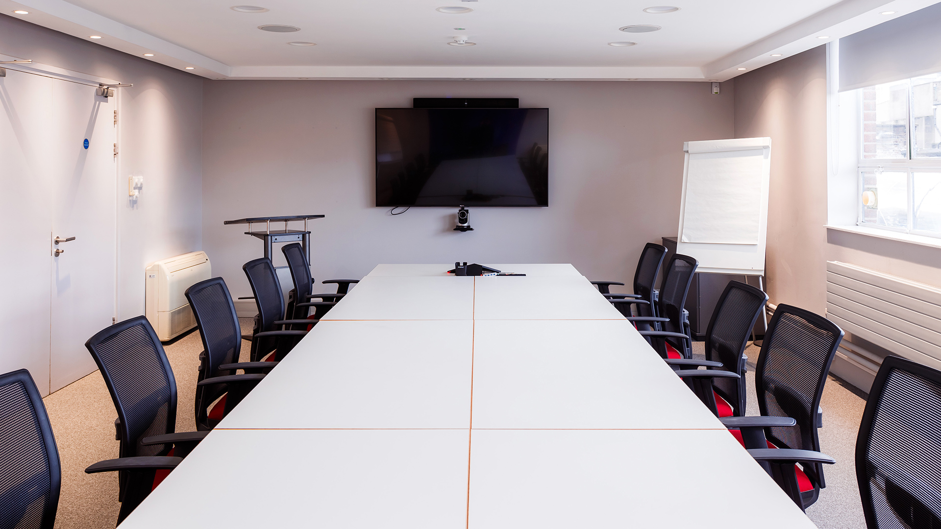A long conference table surrounded by chairs in the large Digital Depot presentation room