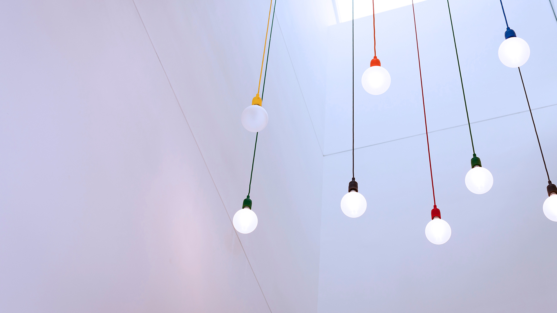 A detail of light bulbs hanging from cords of multiple colours in the Grainstore building