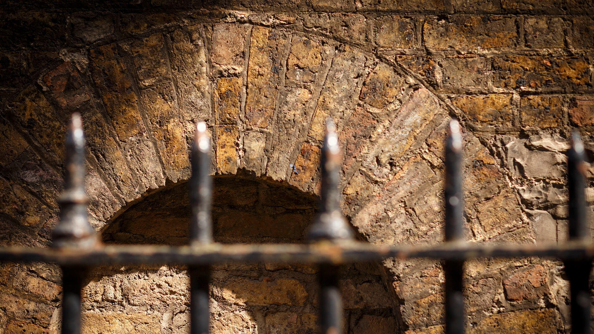 A close-up of an old brickwork wall in the Liberties with iron railings in the foreground