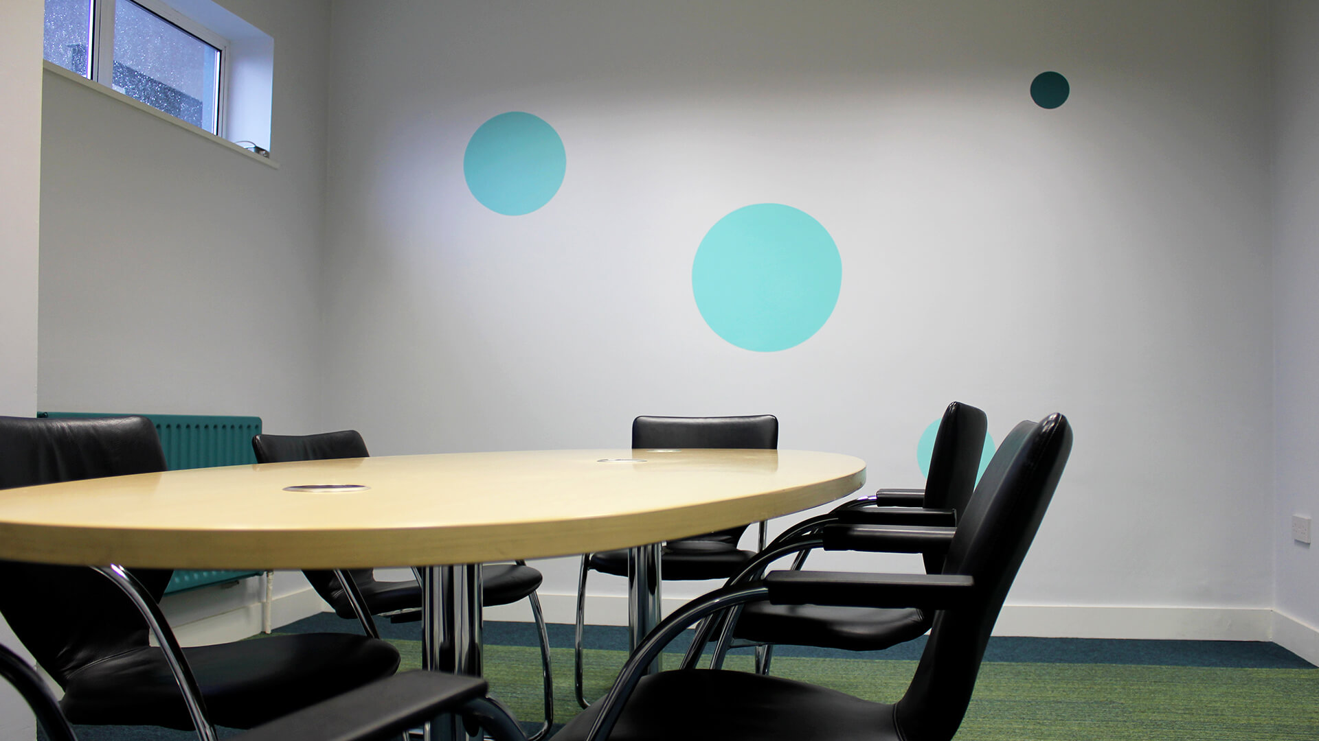 An interior meeting room in the OneFiveSeven building featuring an oval meeting table and modern circular decals on the walls
