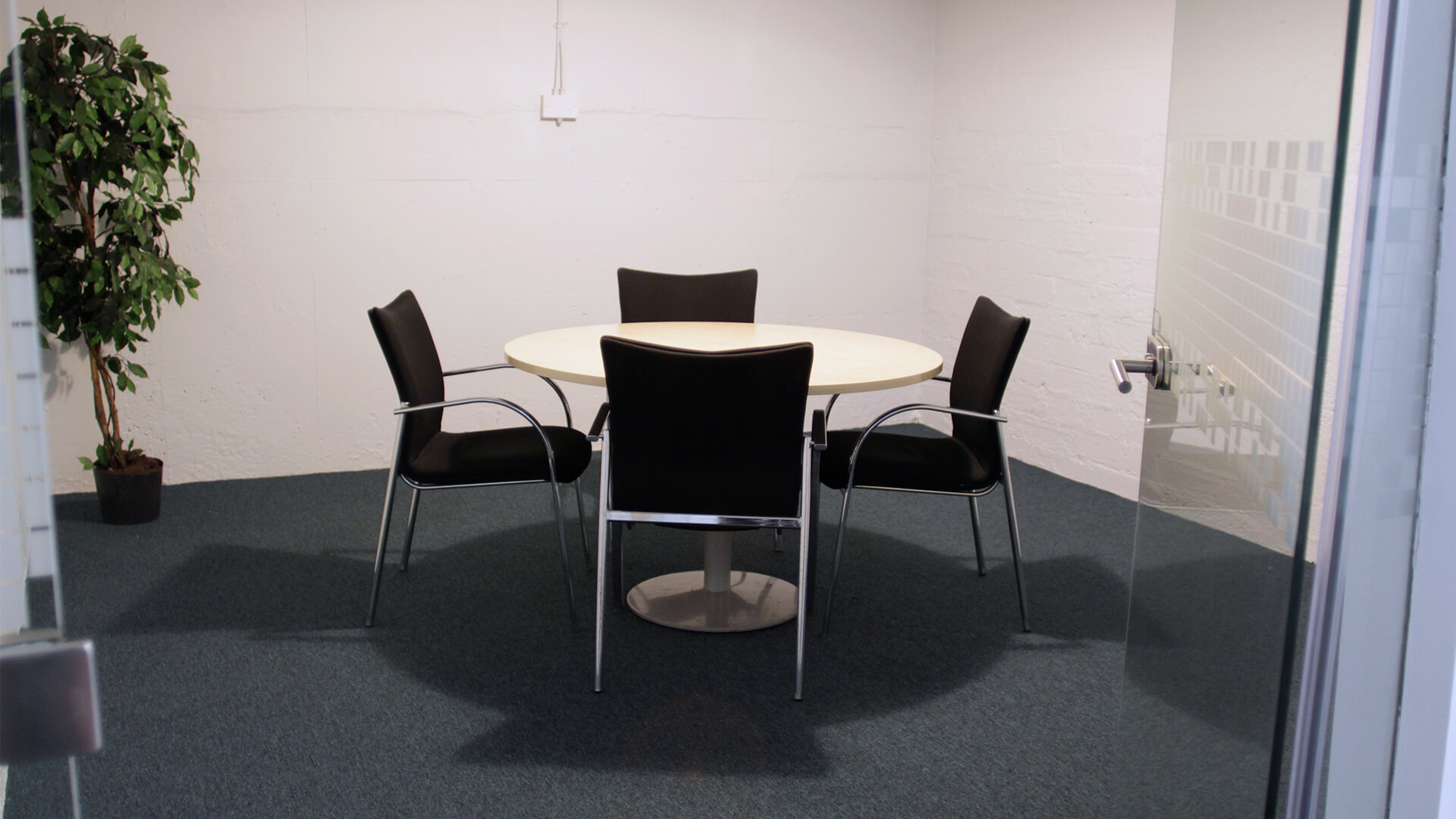 Chairs surround a circular table in an intimate meeting room in the OneFiveSeven building