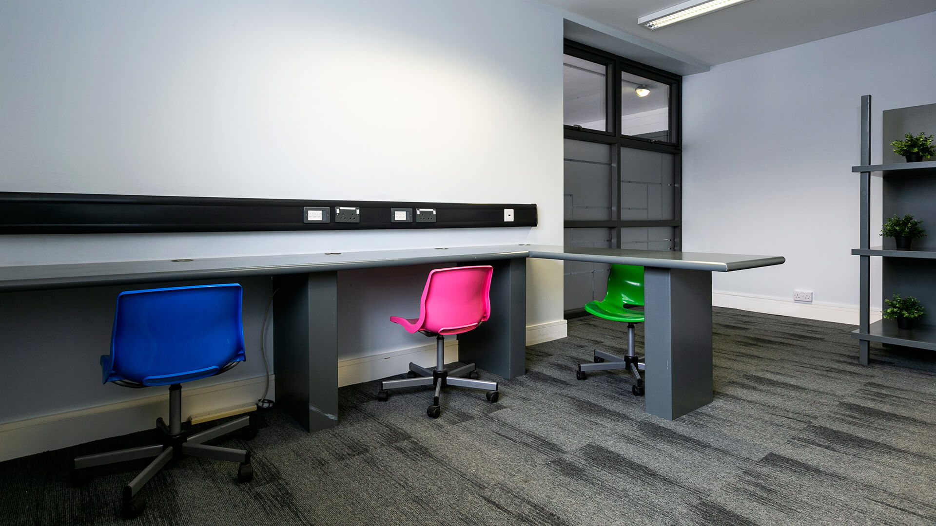 Bright pink, blue and green chairs sit in the iD8 office space