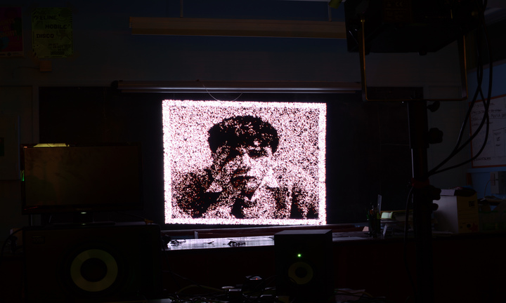 A pixelated, black and white image of a man on a brightly-lit computer screen